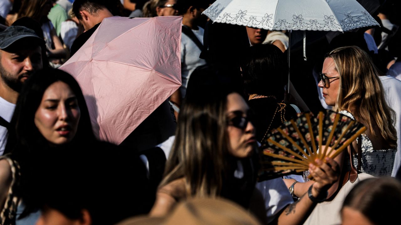 People use umbrellas and a fan for shade amid a red heatwave alert near the Louvre in Paris, Ile-de-France, France, July 12, 2026.