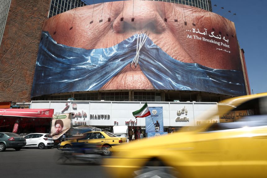 People ride past an anti-US billboard depicting US President Donald Trump and the Strait of Hormuz, in Tehran, Iran, on May 30, 2026.